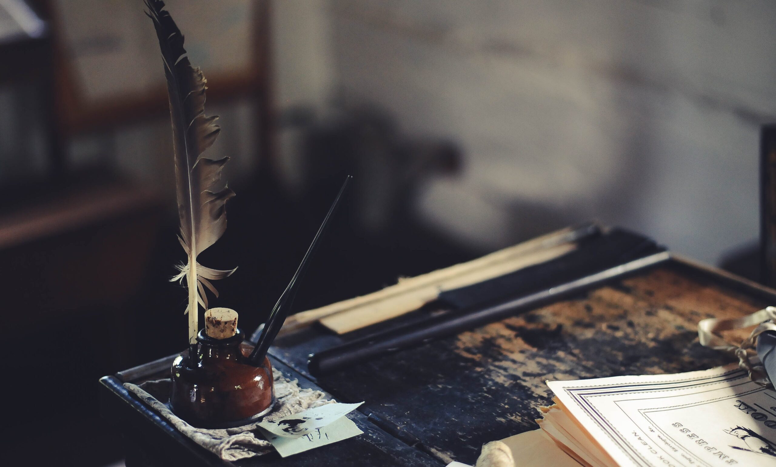 A quill in an inkwell on a desk